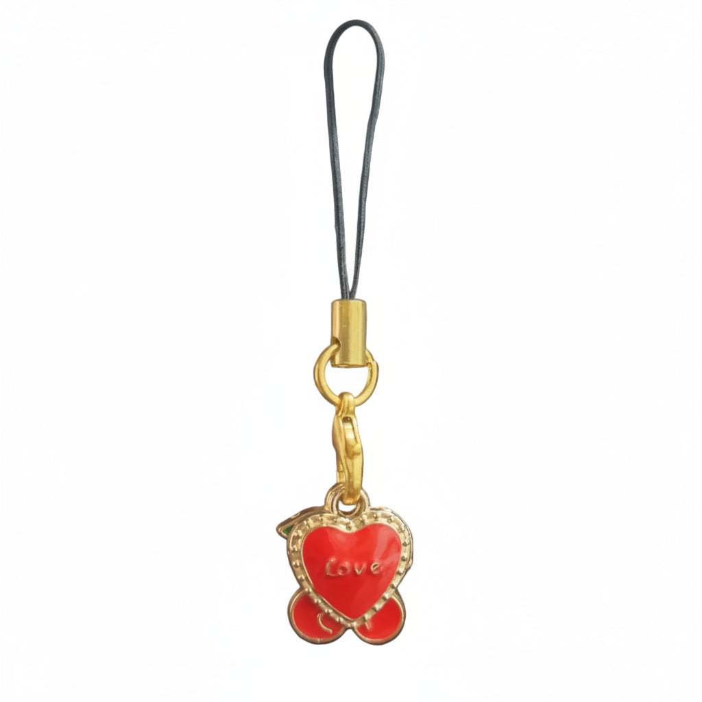 A gold-plated heart-shaped charm with red enamel and the word 'Love' written on it, attached to a black cord, shown against a dark reflective background.